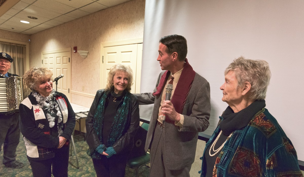 Actor Brian Rohan (Jimmy Stewart/George Bailey) sings "Easy to Love" to Carol Coombs, Karolyn Grimes and Jeanine Roose at the Final Scene Dinner on Sunday night.  Ron Owens accompanied him on the accordion.  Photo by Henry Law