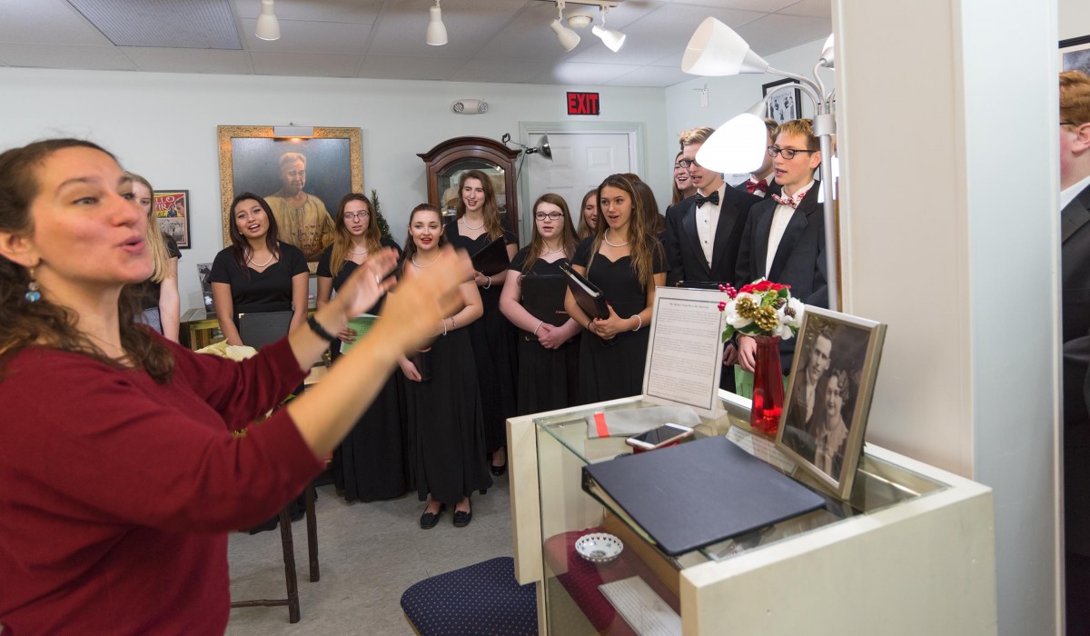 Anna Luisi-Ellis directs the Mynderse Academy Chamber Singers prior to the Press Conference at The Seneca Falls It's a Wonderful Life Museum.  Photo by Henry Law